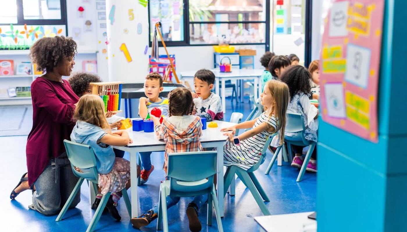 Teacher with nursery children around table